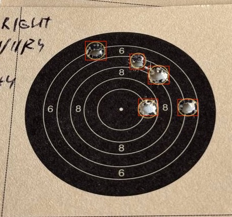 The lower NSRA card from earlier with each bullet hole annotated: a red rectangle tightly bounds the torn paper region of every hole (the bounding box CoreML detects), and a smaller orange circle sits inside each rectangle at the bullet's actual centre (the reach used for scoring).