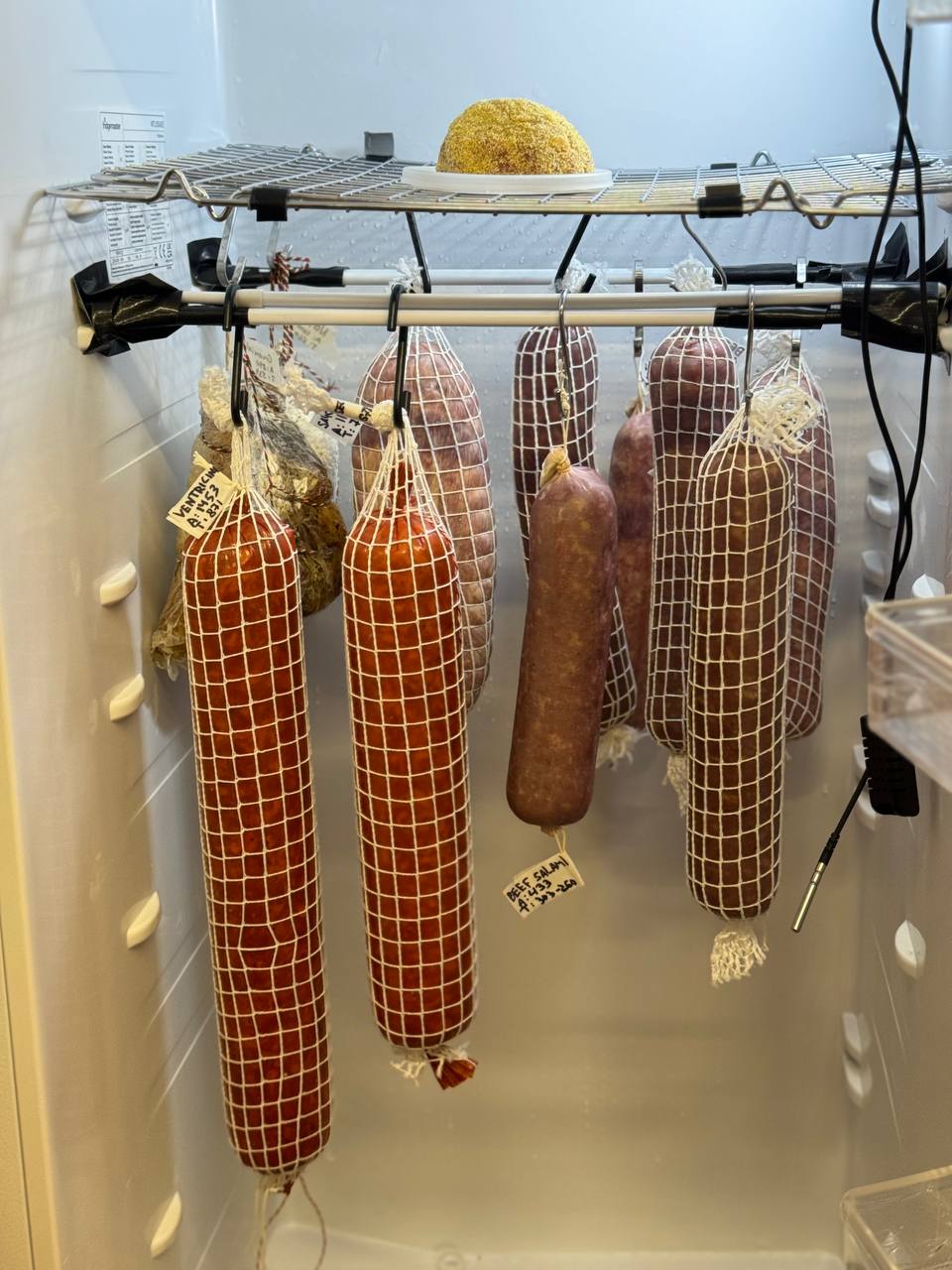 DIY fermentation chamber with controllers taped to a fridge door.